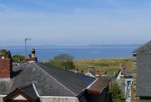 una vista de los tejados de las casas con el océano en el fondo en Byrdir House en Harlech