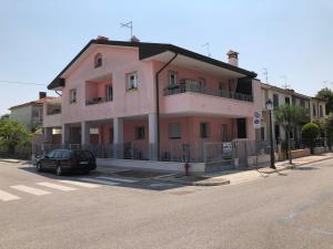 różowy budynek z samochodem zaparkowanym przed nim w obiekcie Casa Pola w Grado