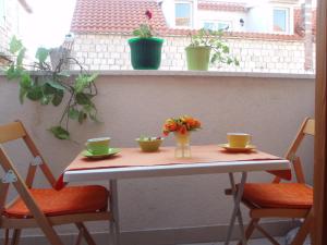 einen Tisch mit zwei Stühlen und zwei Tassen und Blumen darauf in der Unterkunft Studios Magnolia in Trogir