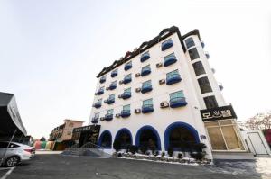 duży biały budynek z niebieskimi oknami i parkingiem w obiekcie Saipan Motel with Sea View w mieście Inczon