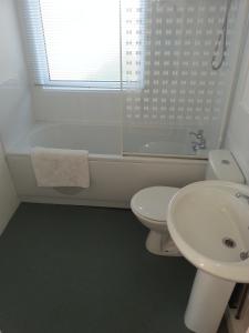 a white bathroom with a sink and a toilet at Beach Cottage in Jaywick Sands