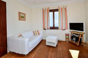 Ferienhaus Villa Kunterbunt في لينداو: غرفة معيشة بها أريكة بيضاء وتلفزيون