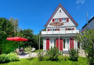 Casa roja y blanca con sombrilla y mesa en Ferienhaus Villa Kunterbunt en Lindau