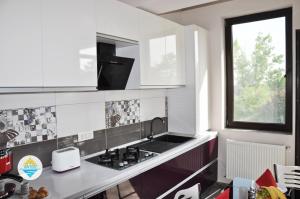 a kitchen with white cabinets and a sink and a window at Antos Deluxe Apartment in Constanţa