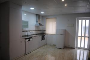 cocina con armarios blancos, fregadero y ventana en Apartaments el tiet, en Sant Carles de la Ràpita