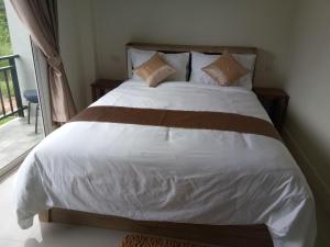 una camera da letto con letto, lenzuola e cuscini bianchi di Supunnika Garden Guesthouse a Fang