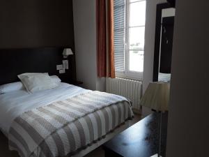 a bedroom with a white bed and a window at Le Relais in Saint-Quentin-les-Anges