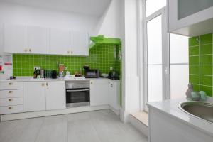 une cuisine avec des placards blancs et du carrelage vert dans l'établissement Cantinho do SAL Apartamento T3, à Aveiro 15 autres photos