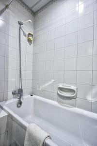 a white bath tub in a bathroom with a toilet at Canifor Hotel in St. Paul's Bay