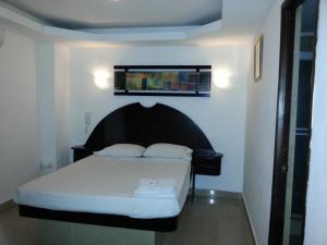 sypialnia z białym łóżkiem z czarnym zagłówkiem w obiekcie Hotel Pension Corona w Panamie