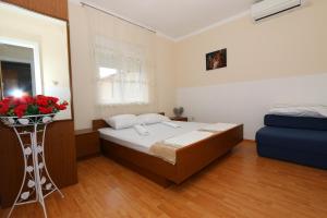 a bedroom with a bed and a vase of red roses at Apartmani Aron in Novalja