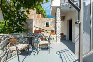 a patio with a table and chairs on a stone wall at Apartment Placido Krk in Krk