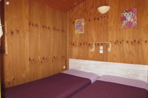 two beds in a room with wooden walls at Le Verger des Ascarines in Corneilla-de-Conflent