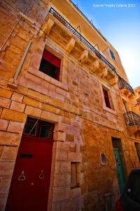 um edifício de tijolos com portas e janelas vermelhas em Twenty Antika em Birgu