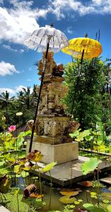 a fountain with two umbrellas in a pond of lilies at deLodtunduh Villa 2 in Ubud