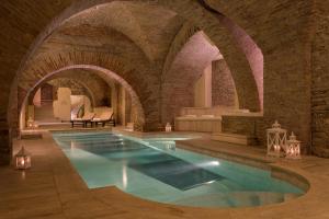 an indoor swimming pool in a building with a brick wall at Sina Brufani in Perugia
