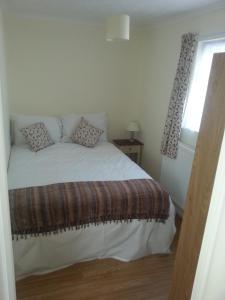 クラクトン・オン・シーにあるSandy Cottageのベッドルーム1室(窓、白いベッド1台付)