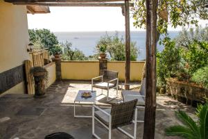 een patio met stoelen en een tafel en de oceaan bij Casa Il Negrito in Massa Lubrense