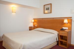 um quarto com uma cama e uma cabeceira em madeira em Hotel do Lago em Braga