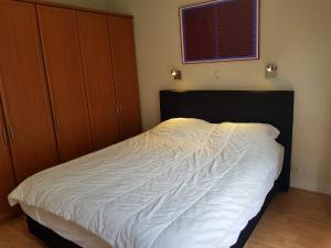 a bedroom with a bed and wooden cabinets and a window at Appartement in residentie Silverbeach met binnenzwembad in De Haan +32 photos