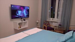 Un dormitorio con una cama con un televisor en la pared. en Comfort In Warsaw Apartment, en Varsovia