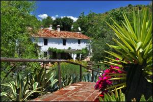 Molino de Las Tablas في Ríogordo: منزل امامه سياج وزهور