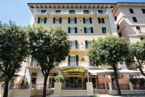 a building with trees in front of it at Hotel Francia E Quirinale in Montecatini Terme