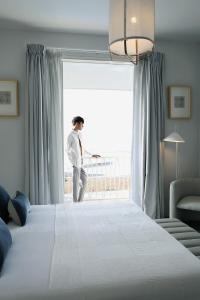 mężczyzna stojący przy dużym oknie w sypialni w obiekcie Studio L w mieście Lovina