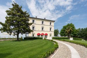 zewnętrzny widok na duży biały dom z podjazdem w obiekcie Relais Villa Belvedere & SPA ONLY ADULTS w mieście Pozzolengo