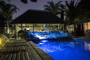 a swimming pool with a resort at night at Aan die Oewer Guesthouse in Graaff-Reinet