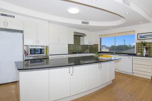 a large kitchen with white cabinets and a large window at Lennox on the Beach Unit 2 - Lennox Head in Lennox Head