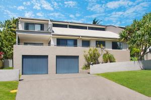 a house with two garage doors in a yard at Pandanus - Lennox Head in Lennox Head