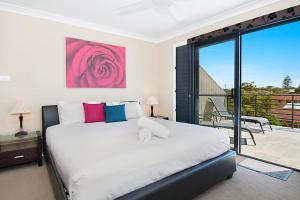 a bedroom with a large bed and a balcony at Pandanus - Lennox Head in Lennox Head