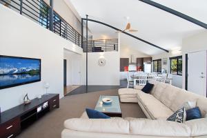 a living room with a white couch and a tv at Pandanus - Lennox Head in Lennox Head