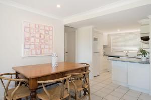 a kitchen with a wooden table and some chairs at Sunrise Reef 4 in Lennox Head