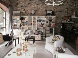 a living room with white furniture and a stone wall at Joanna in Stavroupoli