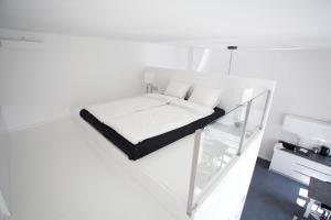 a white bedroom with a bed and a glass staircase at Mini Loft Design in Budapest