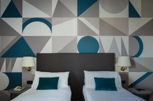 2 łóżka w pokoju hotelowym z malowidłem ściennym w obiekcie Hotel Beatrice w mieście Este
