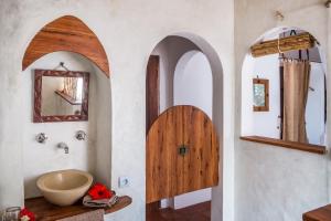 a bathroom with a sink and a wooden door at Baia Sonambula in Praia do Tofo