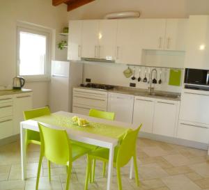 cocina con mesa blanca y sillas verdes en Cà "La Bellavista", en Anzano del Parco