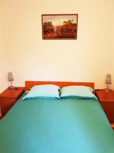een bed met twee kussens en een foto aan de muur bij Apartman Marica in Opatija