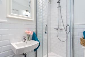 a white bathroom with a sink and a shower at Elite Apartments Center Grobla in Gdańsk