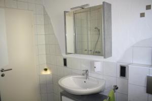 a white bathroom with a sink and a mirror at Ferienwohnung Hengl in Ettenheim +6 photos