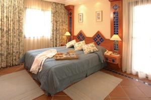 a bedroom with a bed with a tray of food on it at Pine Cliffs Village & Golf Suites in Albufeira