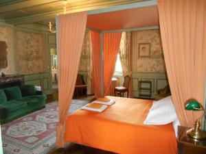 - une chambre avec un lit à baldaquin orange et un canapé dans l'établissement Le Château d'Ailly, à Parigny