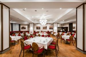 a restaurant with white tables and chairs and a chandelier at Amberton Hotel Klaipeda in Klaipėda