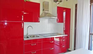 eine rote Küche mit einer Spüle und roten Schränken in der Unterkunft La Quiete 23 Lake view apartment by Gardadomusmea in Tremosine sul Garda