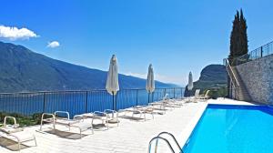 einen Pool mit Liegestühlen und Sonnenschirmen in der Unterkunft La Quiete 23 Lake view apartment by Gardadomusmea in Tremosine sul Garda