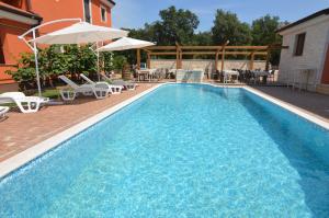 a swimming pool with tables and chairs and an umbrella at Hotel Natura Vilanija in Umag