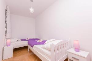 2 Betten in einem Zimmer mit weißen Wänden und lila Lampen in der Unterkunft Apartment Ivanka in Omiš